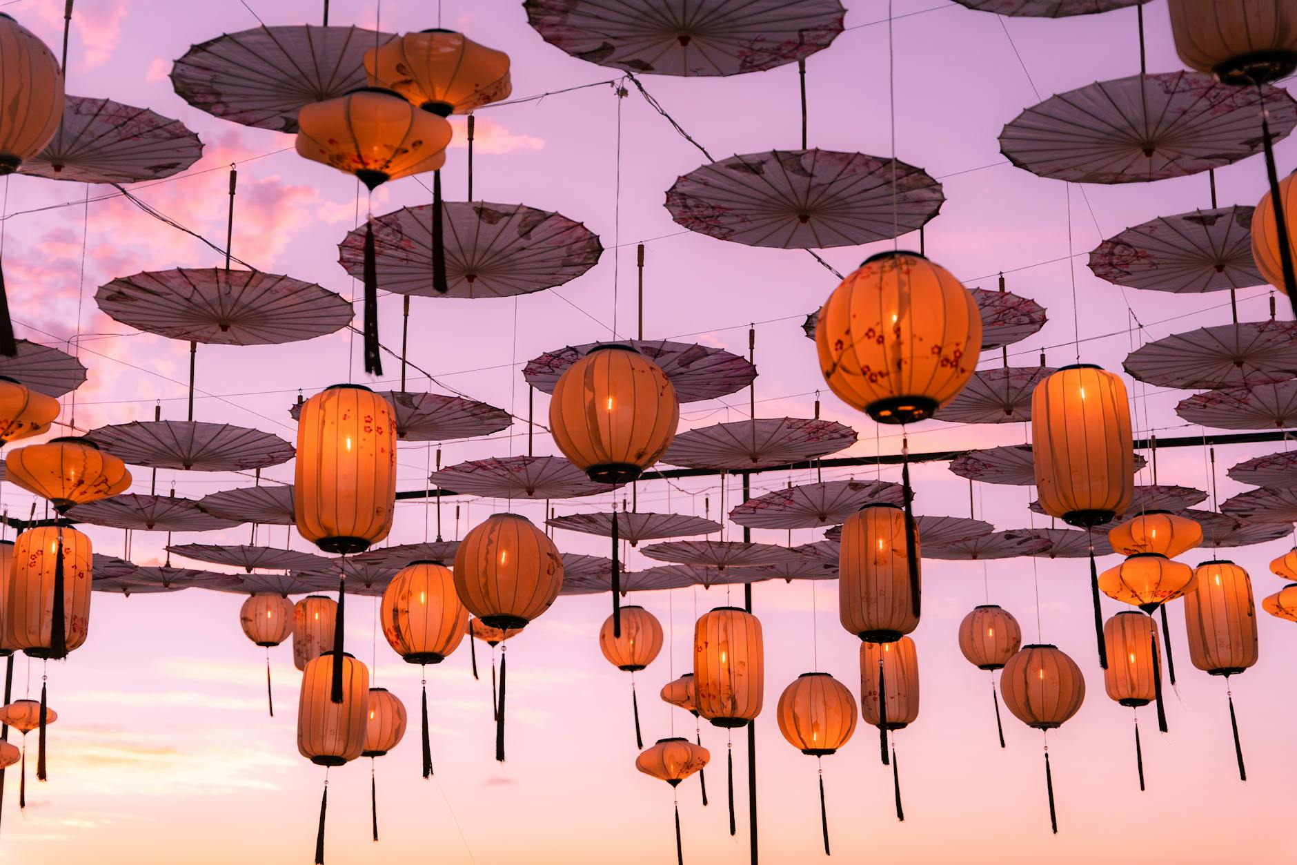 Elegant lanterns and umbrellas under a pink sunset sky in Puerto Vallarta, creating a festive atmosphere.