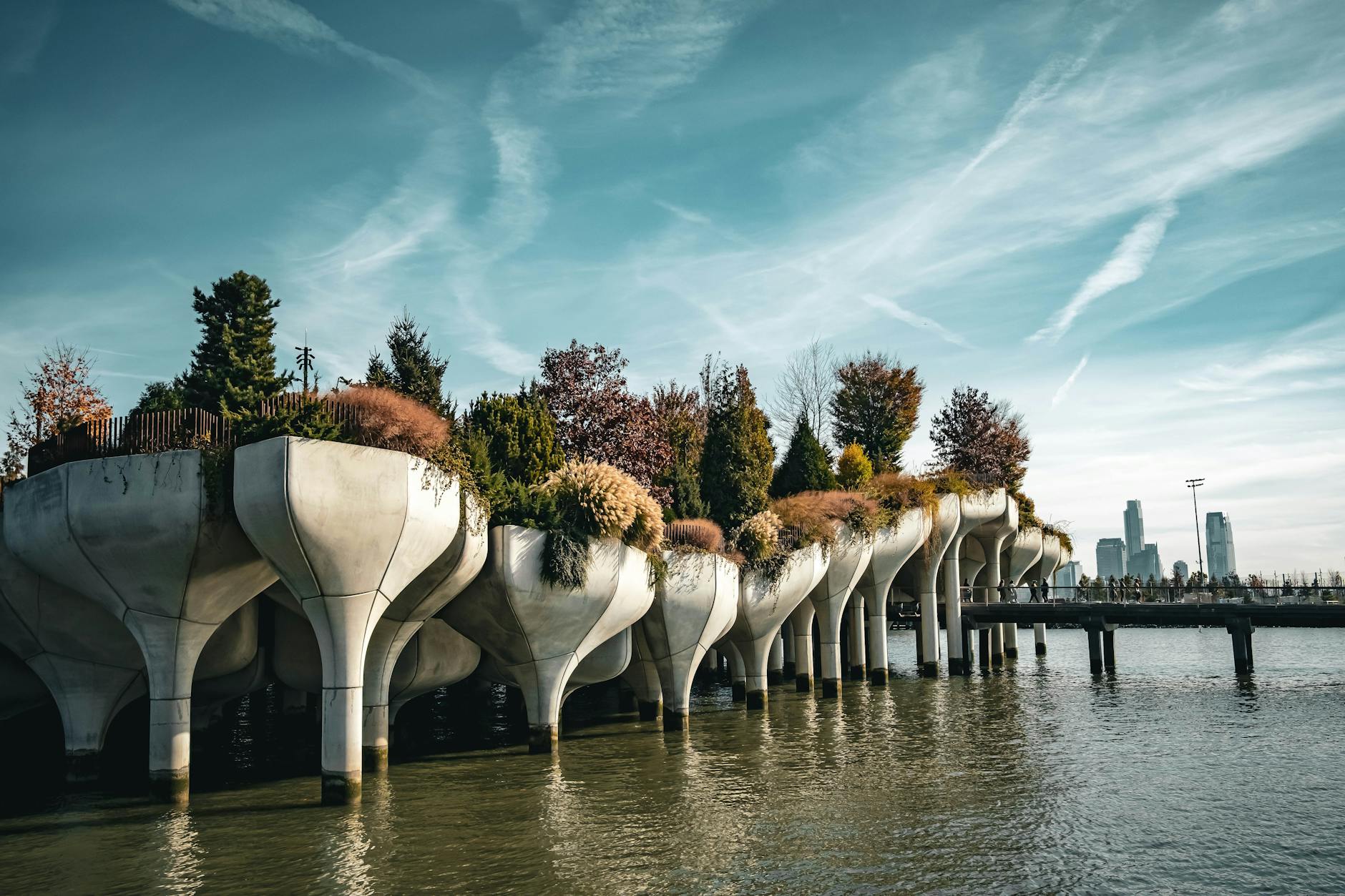 Scenic view of Little Island in Manhattan with clear blue skies and city skyline in the background.