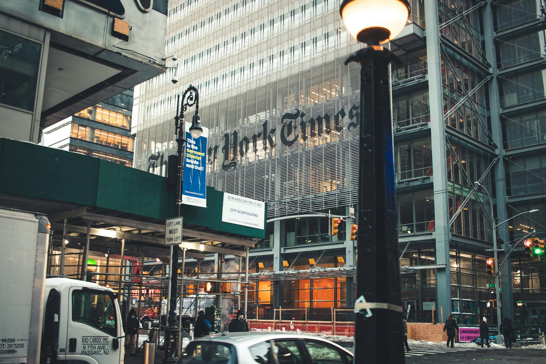 Street view of the New York Times Building in Manhattan with bustling city life and vehicles.