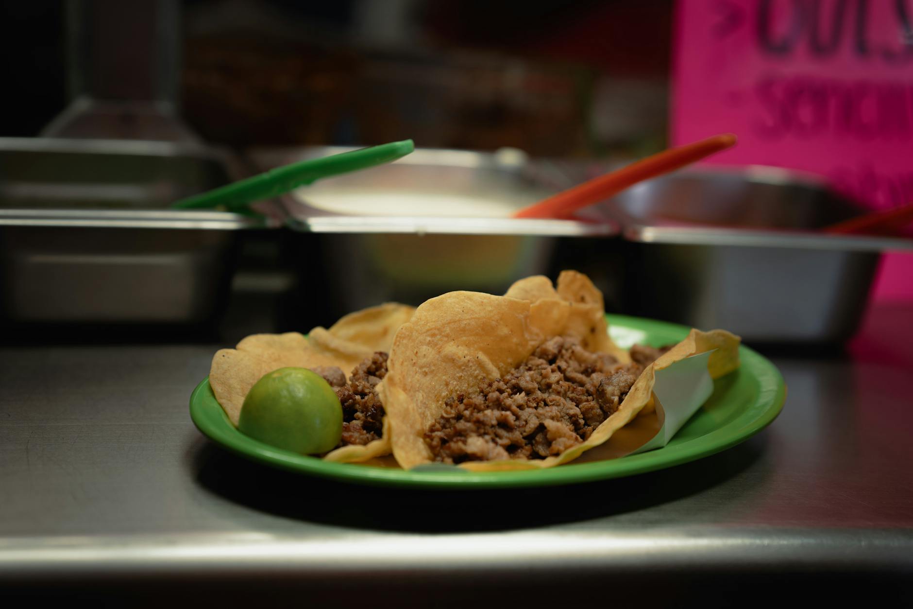 Close-up of delicious tacos with meat and lime, served on a green plate in a Mexican eatery.
