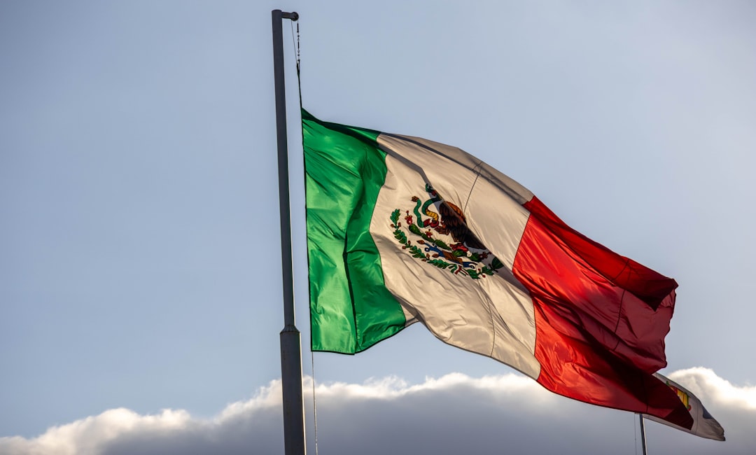 The mexican flag waves proudly against a blue sky.